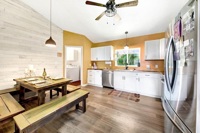 kitchen with lofted ceiling, separate washer and dryer, white cabinetry, light wood-style floors, and appliances with stainless steel finishes