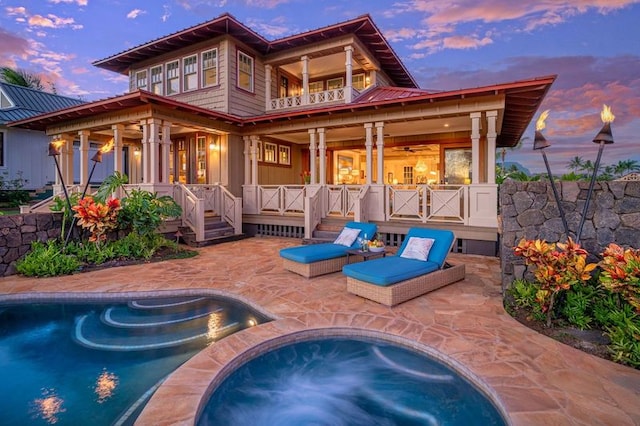 back house at dusk with a patio area and a pool with hot tub