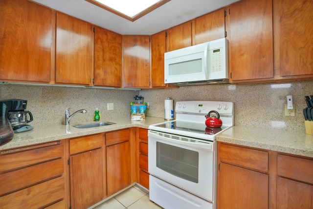 kitchen featuring white appliances, backsplash, sink, and light stone countertops