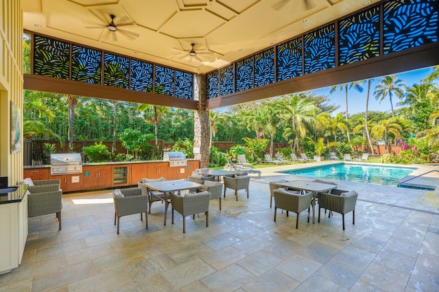 view of patio / terrace with a grill, ceiling fan, a fenced in pool, and exterior kitchen