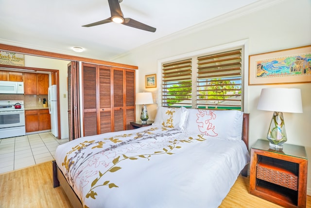 tiled bedroom with ornamental molding, ceiling fan, white fridge, and a closet