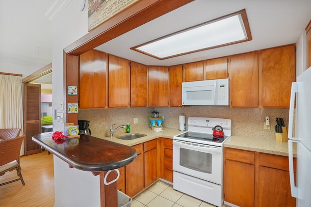 kitchen featuring light hardwood / wood-style flooring, white appliances, sink, kitchen peninsula, and decorative backsplash