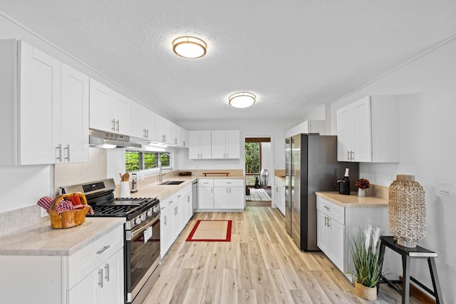 kitchen featuring stainless steel appliances, white cabinetry, plenty of natural light, and sink