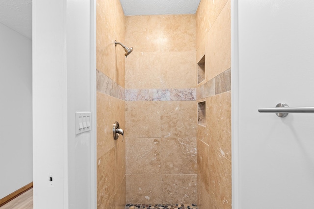 bathroom with tiled shower and a textured ceiling