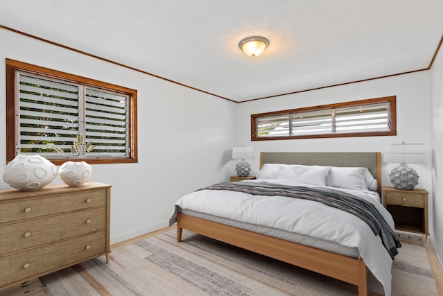 bedroom featuring ornamental molding, a textured ceiling, and light wood-type flooring