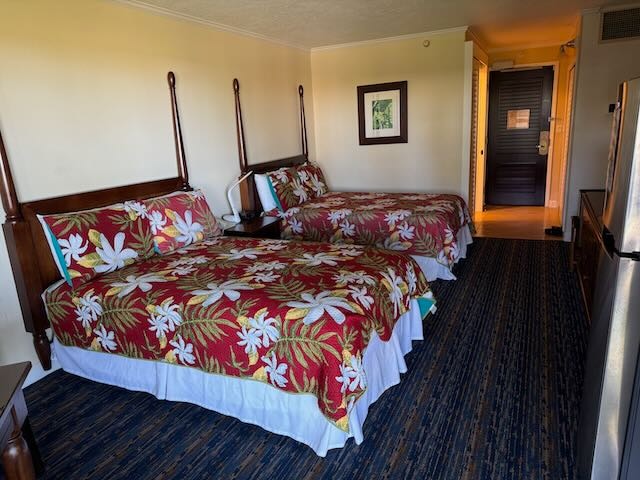 bedroom featuring stainless steel fridge, carpet floors, and ornamental molding