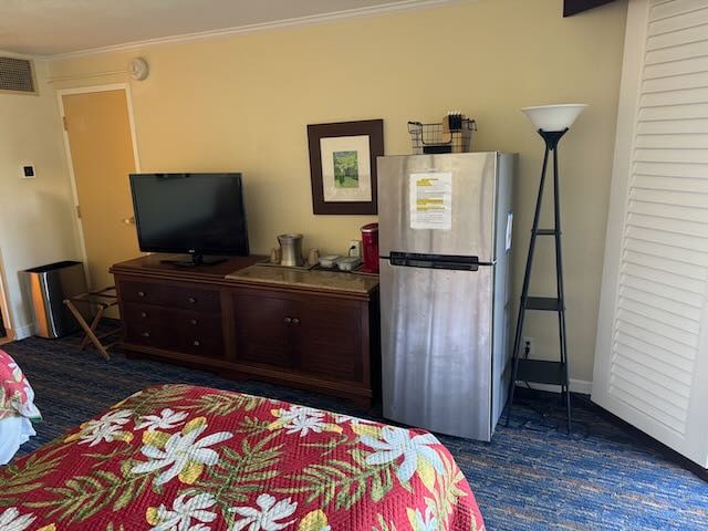 bedroom with crown molding and stainless steel fridge