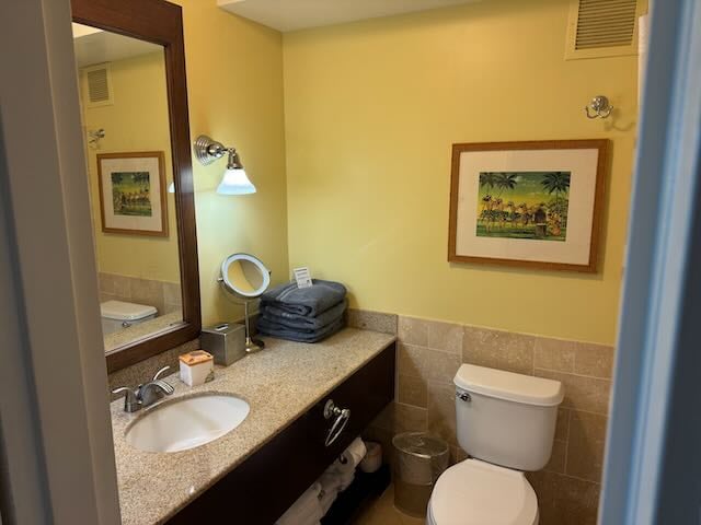 bathroom featuring tile walls, toilet, and vanity