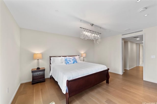 bedroom with hardwood / wood-style floors and an inviting chandelier