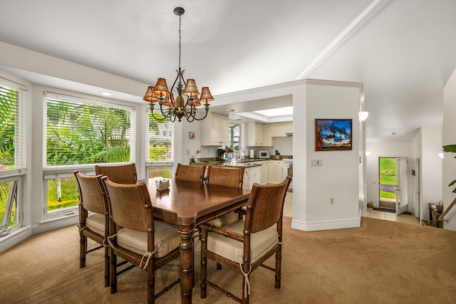 carpeted dining space featuring plenty of natural light, an inviting chandelier, and sink