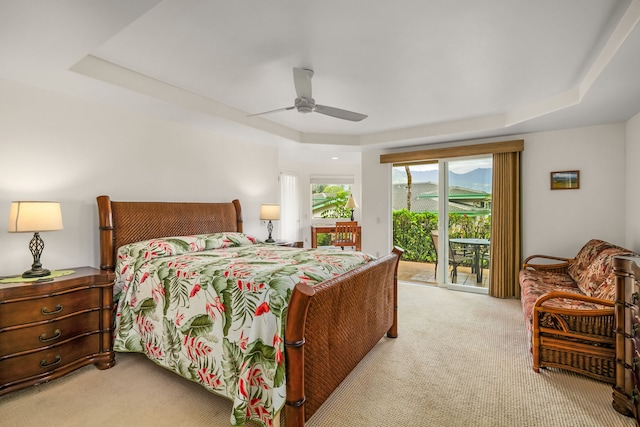 carpeted bedroom featuring ceiling fan, a tray ceiling, and access to outside