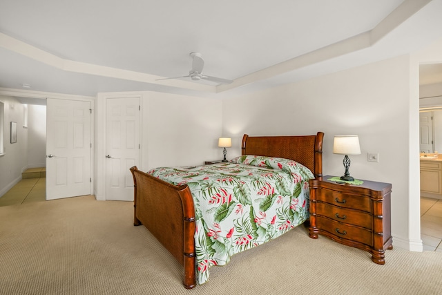 bedroom with ensuite bath, light colored carpet, and ceiling fan