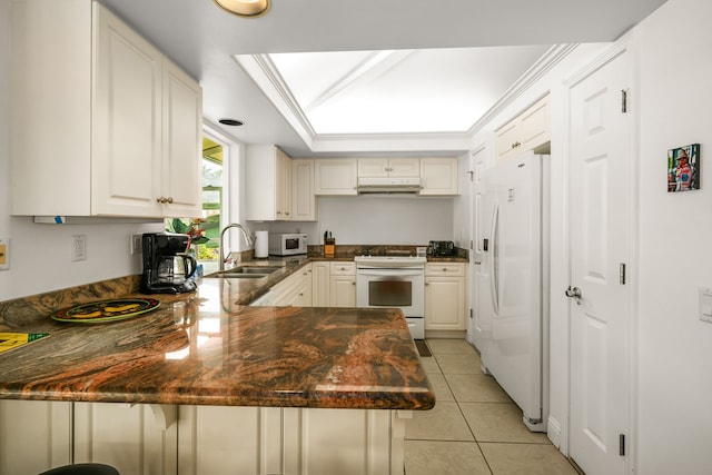 kitchen with a skylight, white appliances, light tile patterned floors, and kitchen peninsula