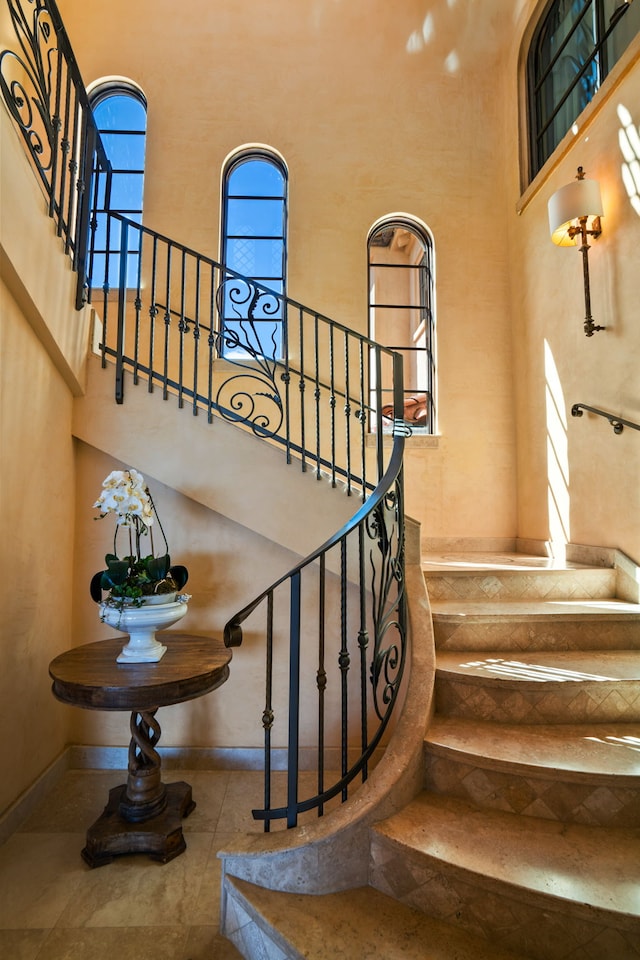 stairway featuring baseboards and a high ceiling