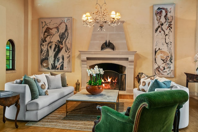 living area with an inviting chandelier, a lit fireplace, and wood finished floors