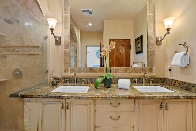 full bath with a tile shower, a sink, visible vents, and double vanity