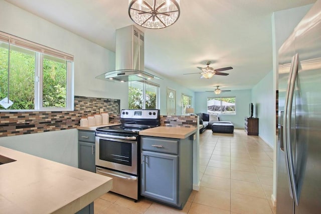 kitchen featuring ceiling fan with notable chandelier, a wealth of natural light, stainless steel appliances, and island exhaust hood