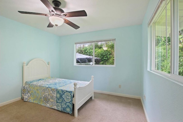 carpeted bedroom featuring ceiling fan and multiple windows