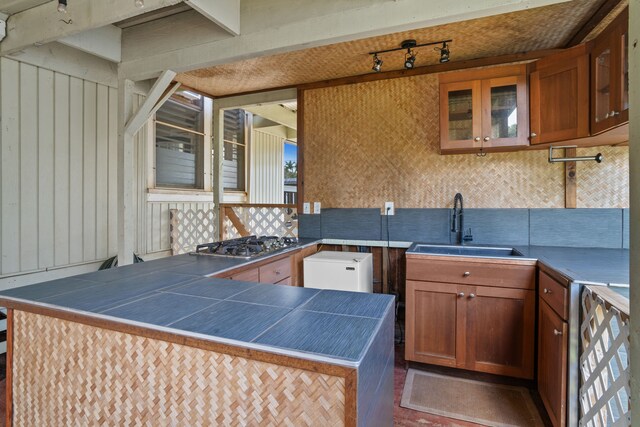 kitchen featuring sink, stainless steel gas stovetop, kitchen peninsula, and tasteful backsplash