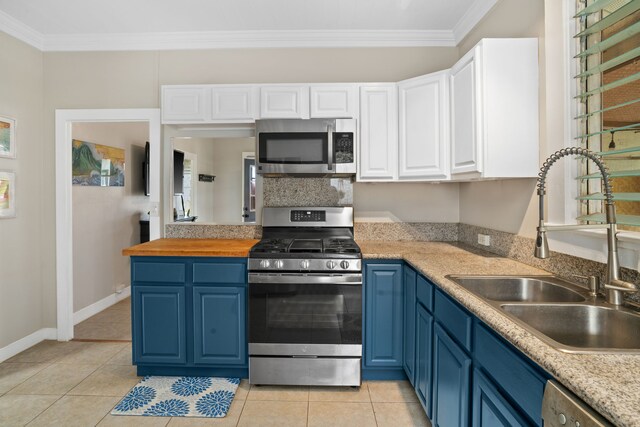 kitchen featuring white cabinetry, appliances with stainless steel finishes, light tile patterned floors, and blue cabinetry