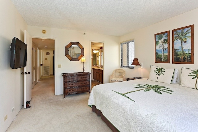 bedroom with light colored carpet, a textured ceiling, and ensuite bath