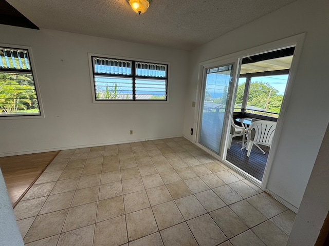 tiled empty room with a textured ceiling