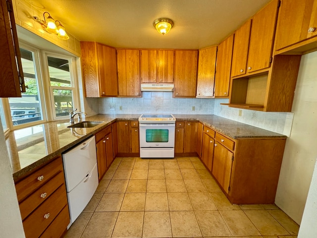 kitchen featuring dark stone counters, sink, backsplash, white appliances, and light tile patterned floors