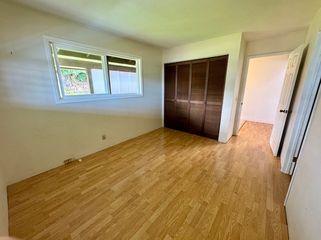 unfurnished bedroom with light hardwood / wood-style flooring and a closet