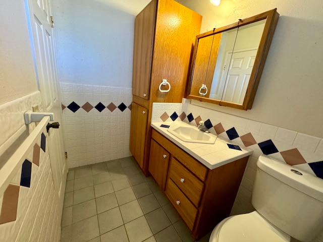 bathroom featuring vanity, tile walls, tile patterned flooring, and toilet