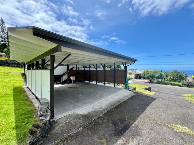 view of parking with a lawn and a carport