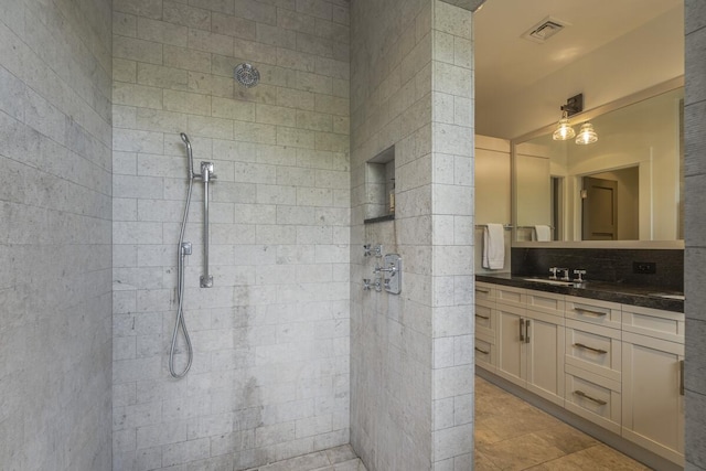 bathroom featuring tile patterned floors, visible vents, tiled shower, and vanity