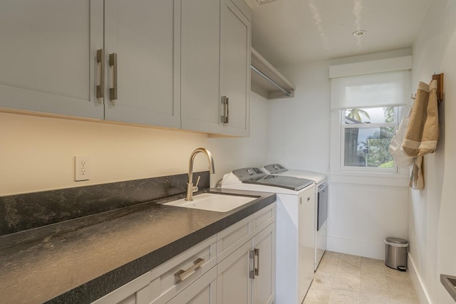 clothes washing area featuring a sink, baseboards, cabinet space, and washing machine and dryer