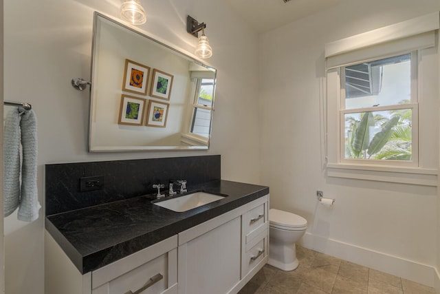 bathroom with vanity, toilet, baseboards, and tile patterned flooring