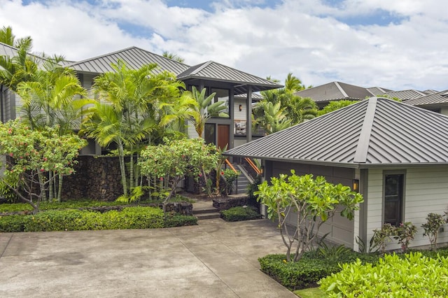 view of front of house featuring a garage, driveway, a standing seam roof, metal roof, and stairs