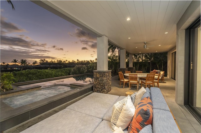 patio terrace at dusk featuring ceiling fan, an outdoor hangout area, an in ground hot tub, and outdoor dining space