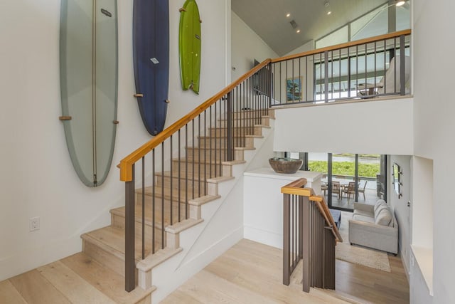 staircase with recessed lighting, wood finished floors, and high vaulted ceiling