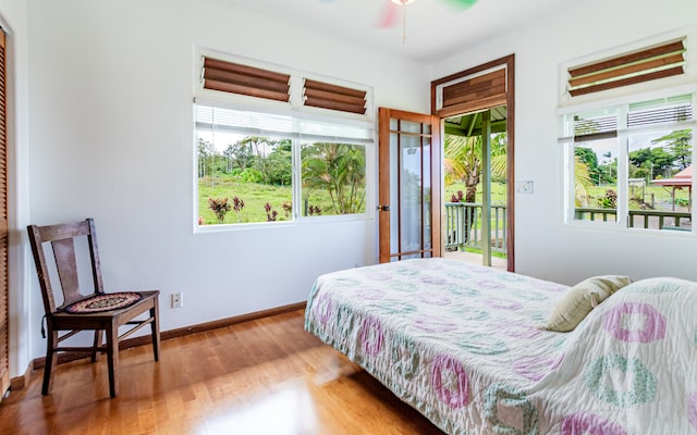 bedroom with access to exterior, wood-type flooring, and ceiling fan