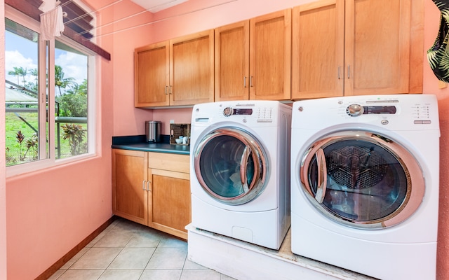 laundry area featuring light tile patterned floors, washing machine and clothes dryer, a healthy amount of sunlight, and cabinets