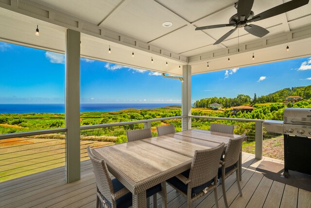 wooden terrace with grilling area, a water view, and ceiling fan