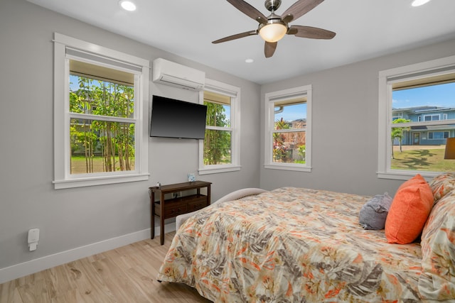 bedroom with a wall mounted AC, ceiling fan, and light hardwood / wood-style flooring