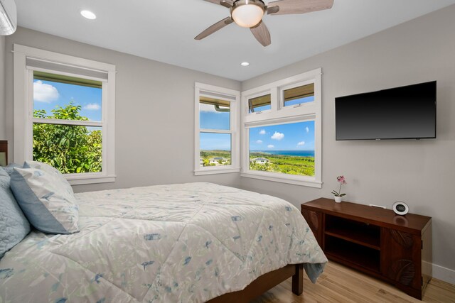 bedroom featuring ceiling fan, multiple windows, and light hardwood / wood-style floors