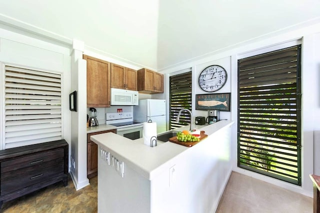 kitchen with sink, kitchen peninsula, and white appliances