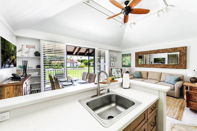 kitchen featuring sink, vaulted ceiling, rail lighting, light carpet, and ceiling fan