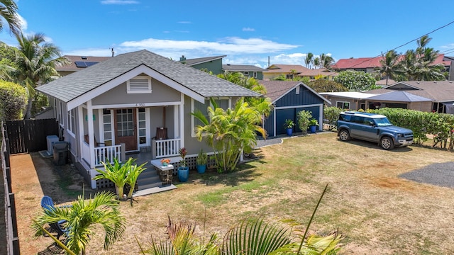 view of front of house with a garage, covered porch, a front lawn, and an outbuilding