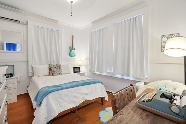 bedroom featuring a wall mounted AC, dark hardwood / wood-style flooring, and ornamental molding