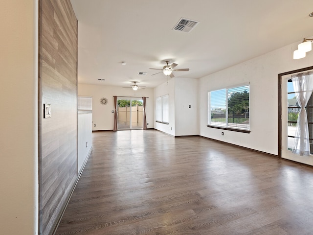 unfurnished living room featuring ceiling fan, plenty of natural light, and dark hardwood / wood-style flooring