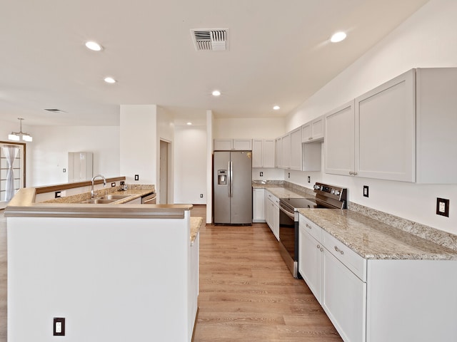 kitchen featuring appliances with stainless steel finishes, hanging light fixtures, white cabinetry, light wood-type flooring, and sink