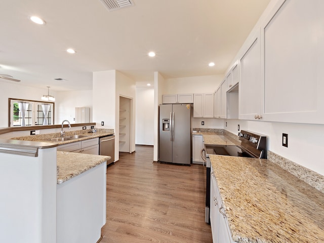 kitchen with light hardwood / wood-style floors, sink, white cabinetry, appliances with stainless steel finishes, and decorative light fixtures