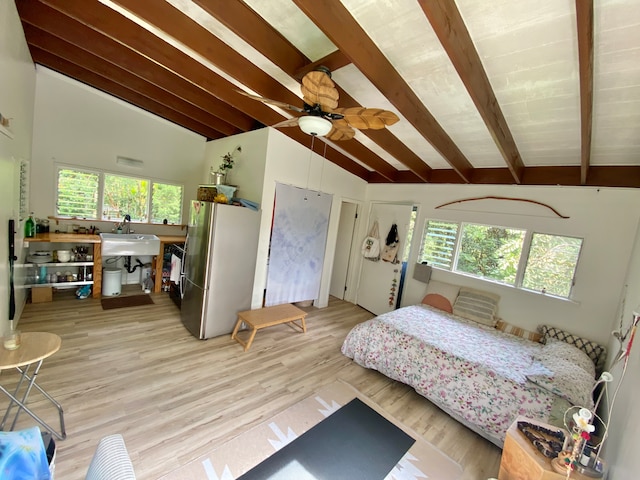 bedroom with lofted ceiling with beams, multiple windows, stainless steel fridge, and ceiling fan