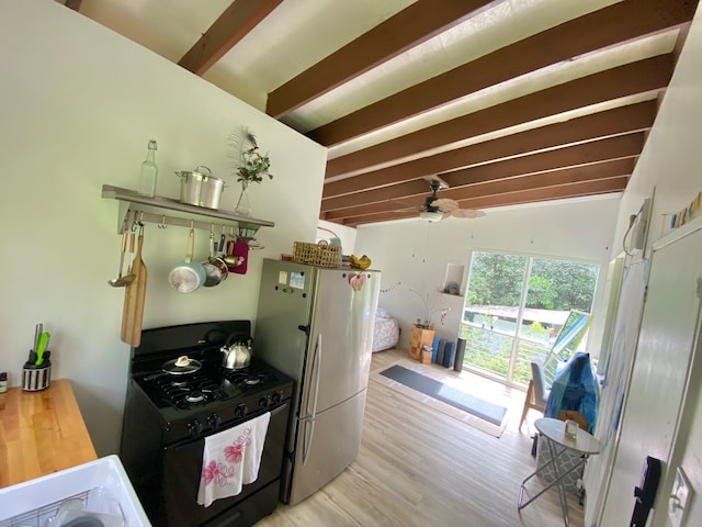 kitchen featuring lofted ceiling with beams, light hardwood / wood-style flooring, stainless steel fridge, black range with gas stovetop, and ceiling fan